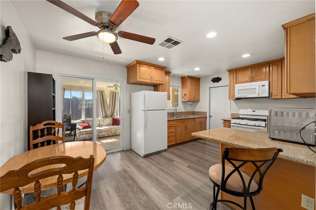 12610 Serrano Drive Yucaipa, CA 92399 - Photo 5 of 29 a kitchen with stainless steel appliances granite countertop a dining table chairs refrigerator and microwave