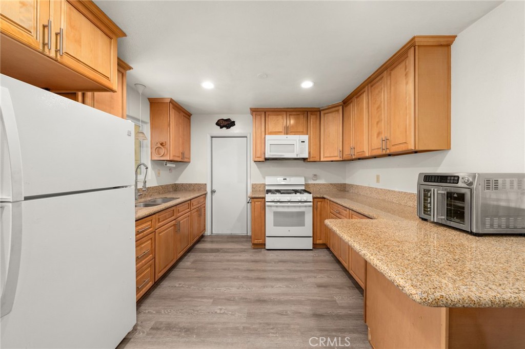 12610 Serrano Drive Yucaipa, CA 92399 - Photo 6 of 29 a kitchen with granite countertop a refrigerator stove top oven and cabinets