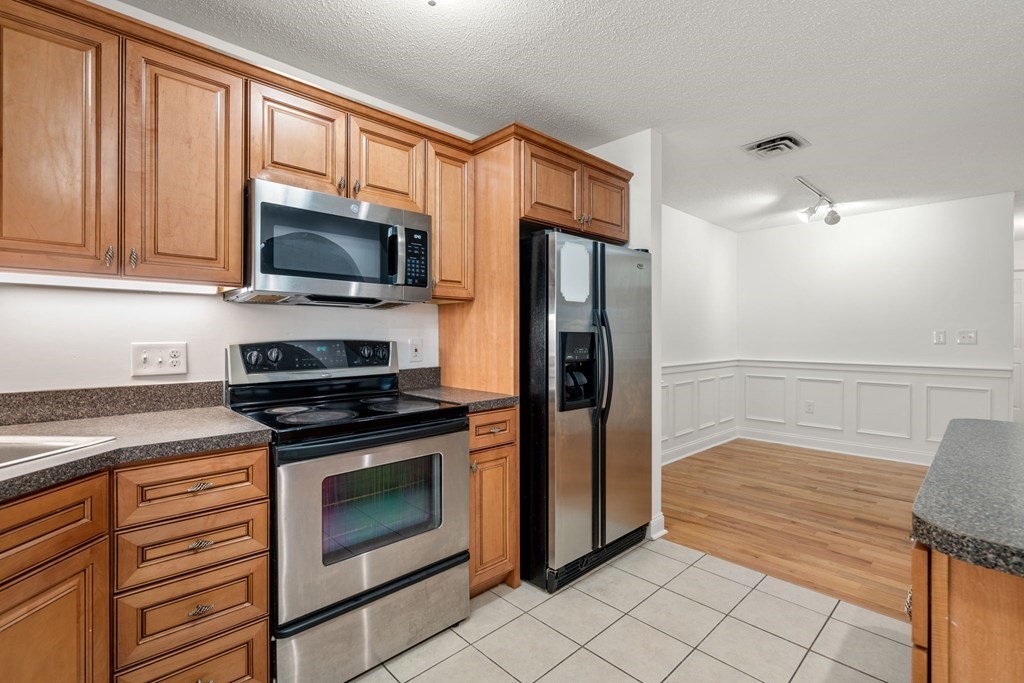 100 Brookside Drive, Unit F Andover, MA 01810 - Photo 6 of 22 a kitchen with stainless steel appliances granite countertop a refrigerator and a stove top oven