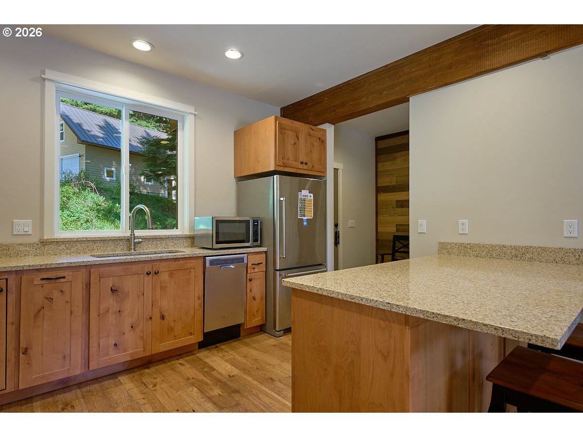 64368 Tamarack Road Lostine, OR 97857 - Photo 12 of 39 a kitchen with stainless steel appliances granite countertop a refrigerator a sink dishwasher and wooden cabinets with a large window