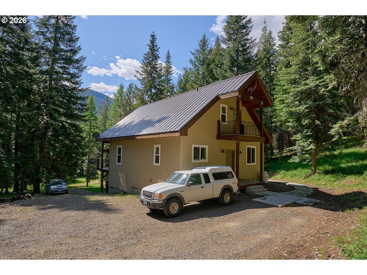 64368 Tamarack Road Lostine, OR 97857 - Photo 3 of 39 a view of a white house and a car parked in front of it