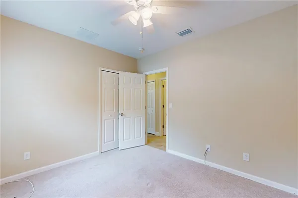an empty room with a chandelier fan and closet area
