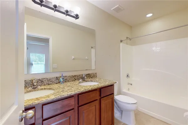 a bathroom with a granite countertop sink toilet and shower