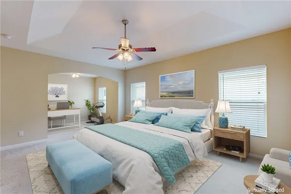 a spacious bedroom with a bed a chandelier and a couch