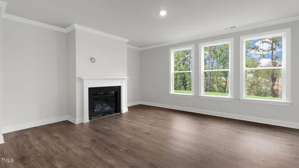 an empty room with wooden floor fireplace and windows