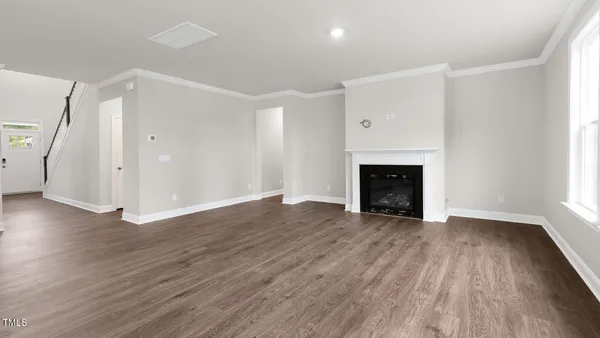 an empty room with wooden floor fireplace and windows