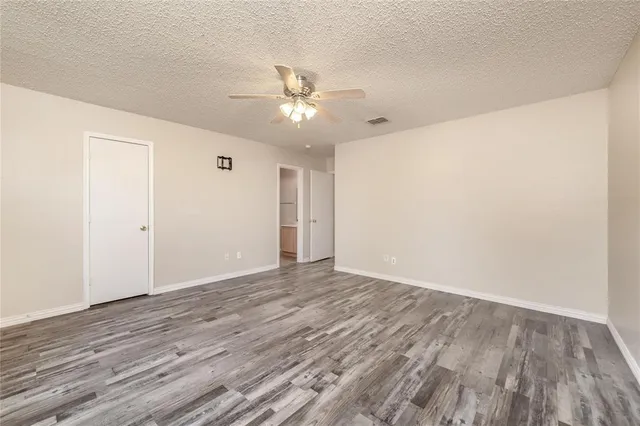 an empty room with wooden floor ceiling fan and windows