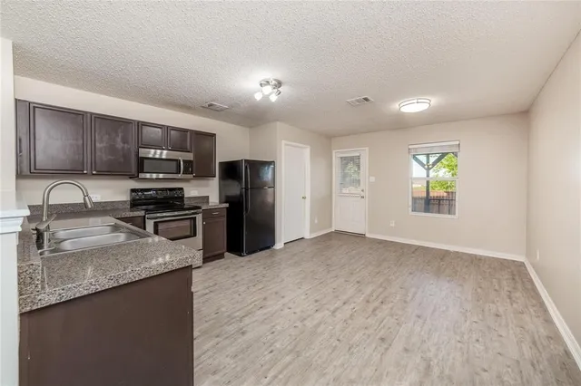 a kitchen with granite countertop stainless steel appliances a refrigerator stove microwave and sink