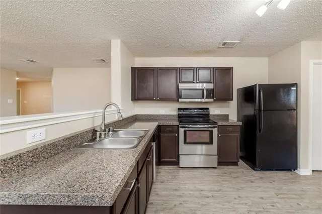 a kitchen with granite countertop a refrigerator and a sink
