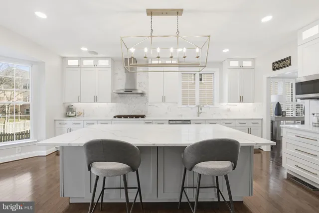 a kitchen with kitchen island granite countertop a dining table chairs and white cabinets