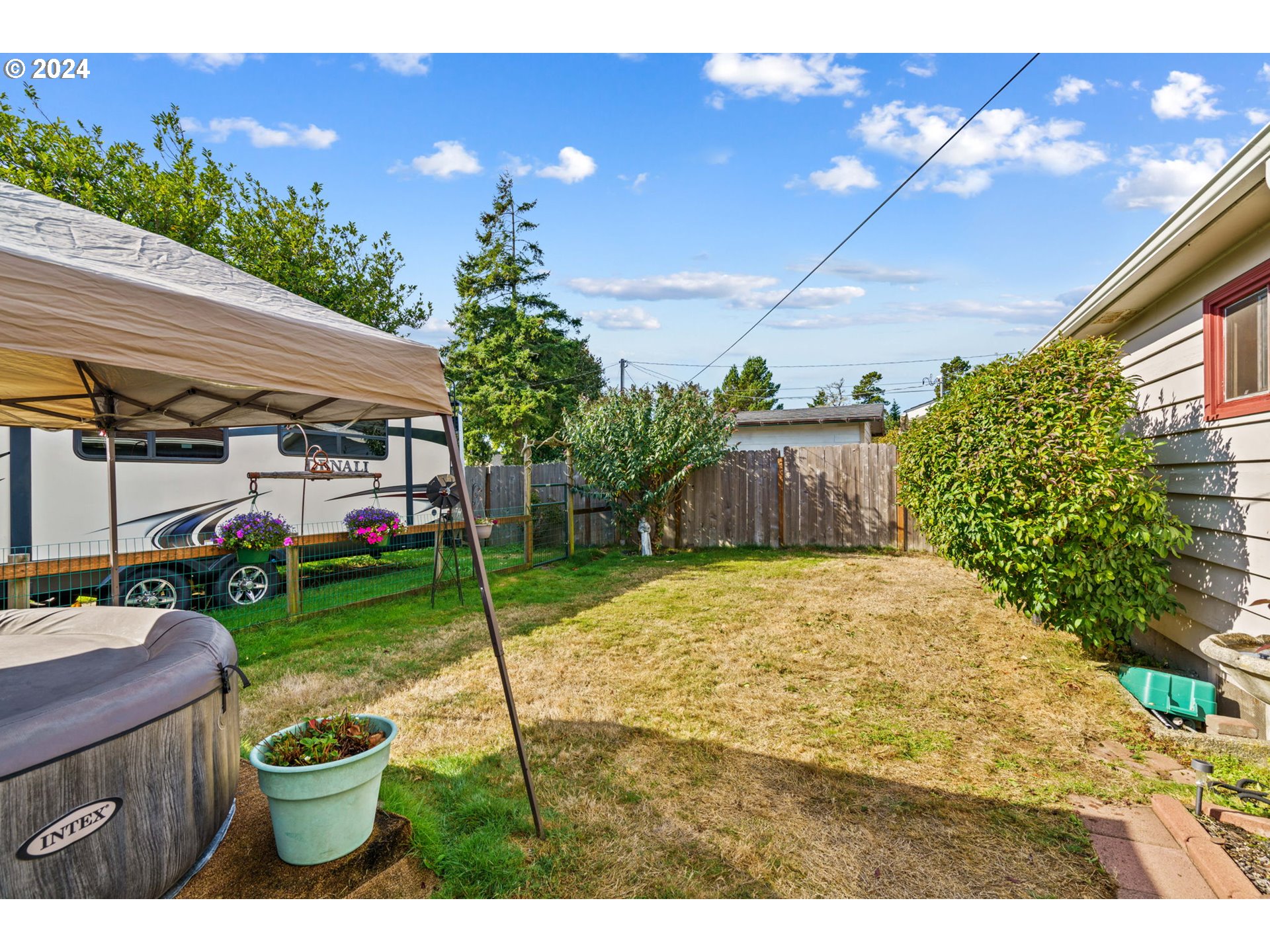 2290 18th Street Florence, OR 97439 - Photo 26 of 32 a backyard of a house with table and chairs potted plants and a large tree