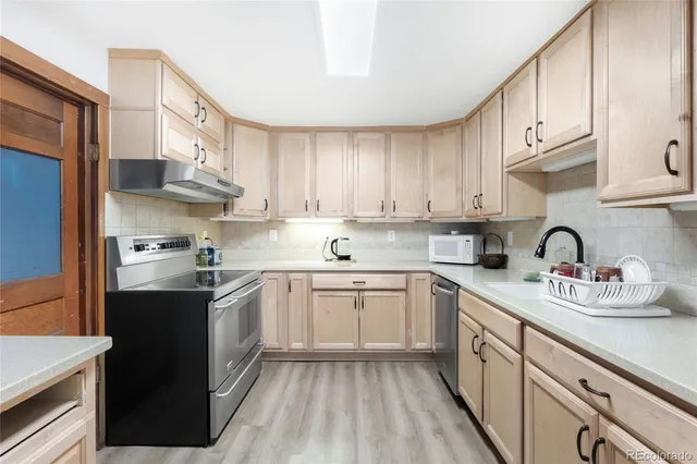 a kitchen with stainless steel appliances granite countertop a sink stove refrigerator and cabinets