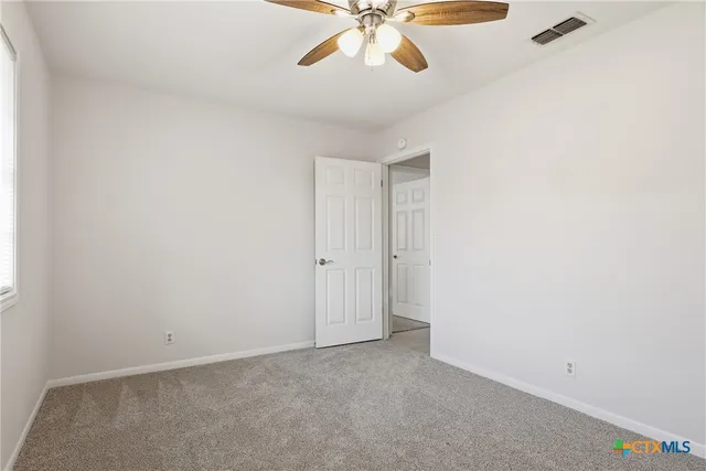 an empty room with a window and a fan