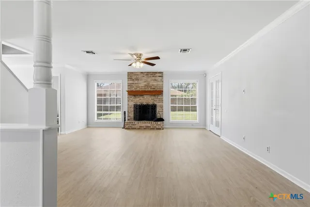 an empty room with windows and fireplace