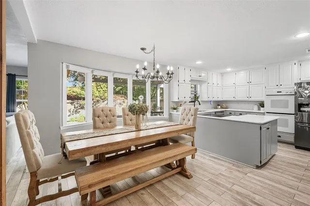 a kitchen with a stove a sink dishwasher and white cabinets with wooden floor