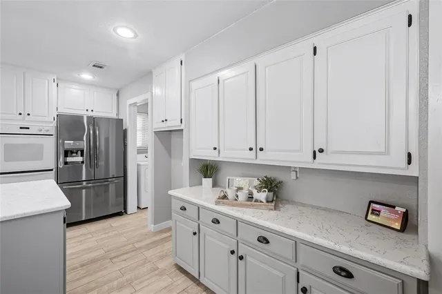 a kitchen with stainless steel appliances granite countertop a refrigerator sink and white cabinets
