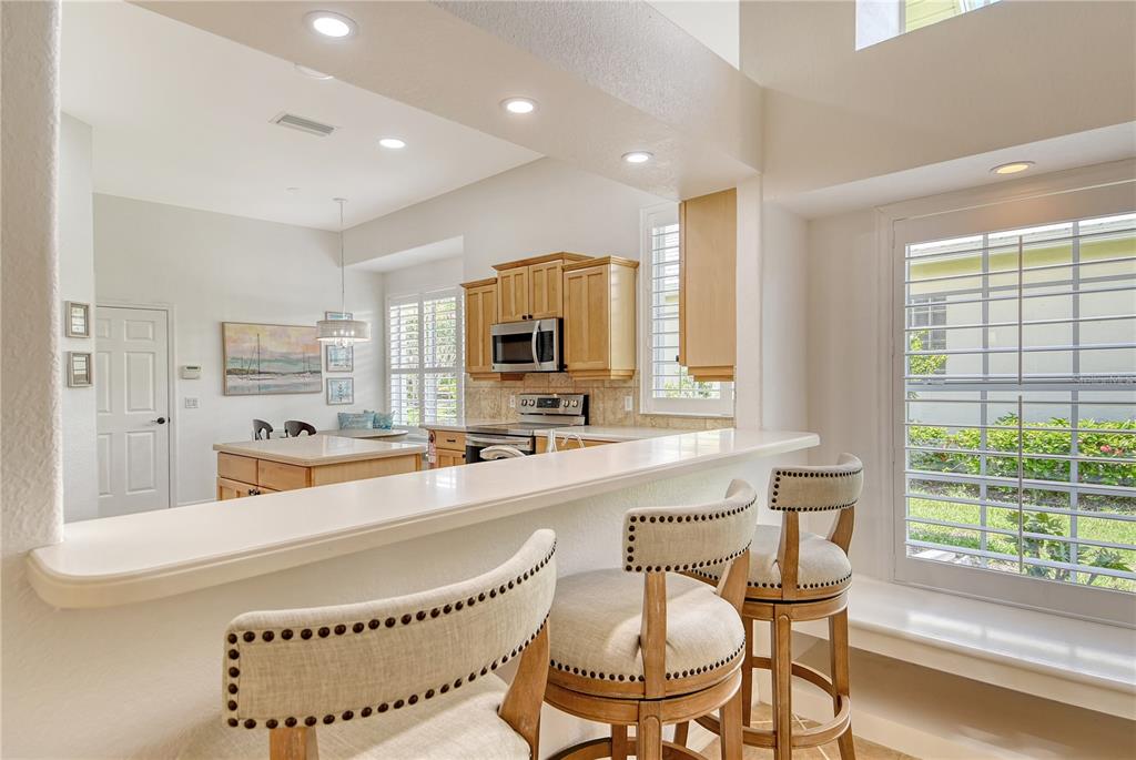 340 Bermuda Court, Unit 5 Venice, FL 34293 - Photo 14 of 52 a large white kitchen with granite countertop a stove a sink a dining table and chairs