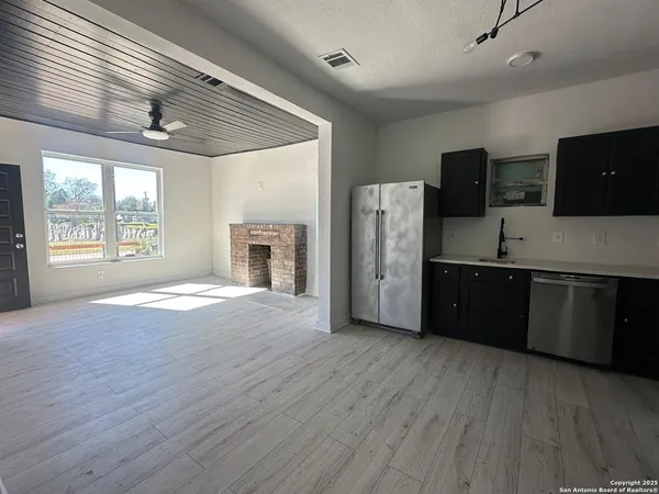 a kitchen with stainless steel appliances granite countertop a refrigerator a sink dishwasher a stove and a wooden floors