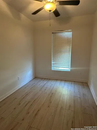 an empty room with wooden floor fan and windows