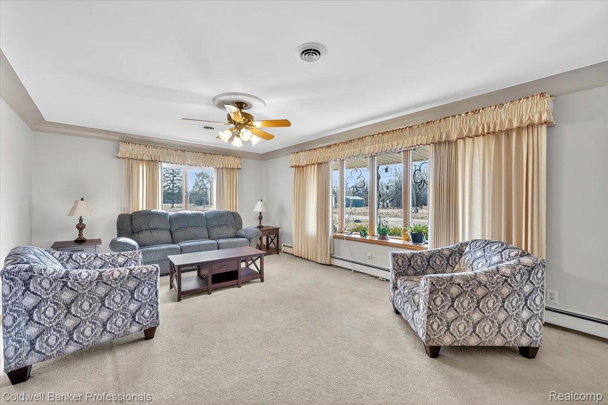 7410 Wilson Road Montrose, MI 48457 - Photo 11 of 38 Living room with a ceiling fan, light colored carpet, crown molding, and a baseboard radiator