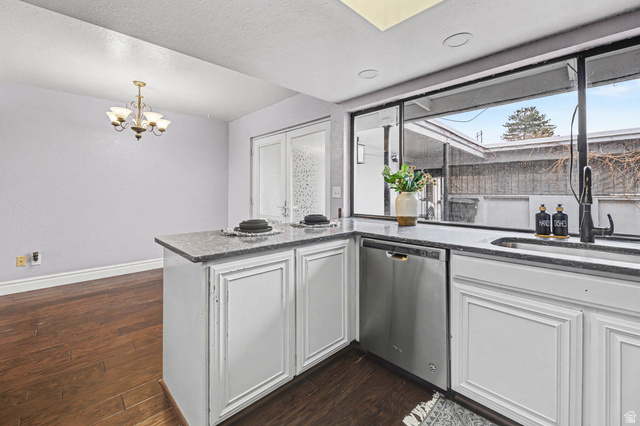 34 Benchmark Village Tooele, UT 84074 - Photo 11 of 35 Kitchen with a peninsula, white cabinets, dishwasher, dark wood finished floors, and dark stone countertops