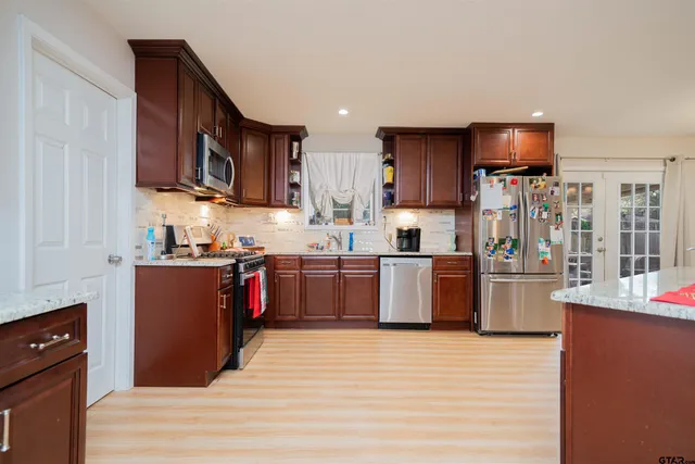 a kitchen with stainless steel appliances kitchen island granite countertop a refrigerator stove top oven and sink