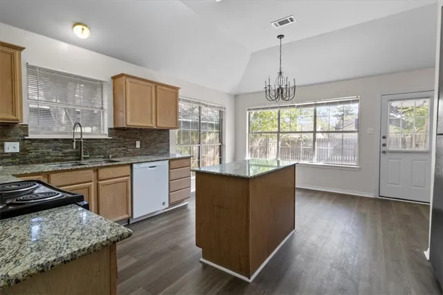 a kitchen with granite countertop wooden floors and wide window