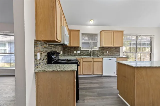 a kitchen with stainless steel appliances granite countertop a stove a sink and a microwave