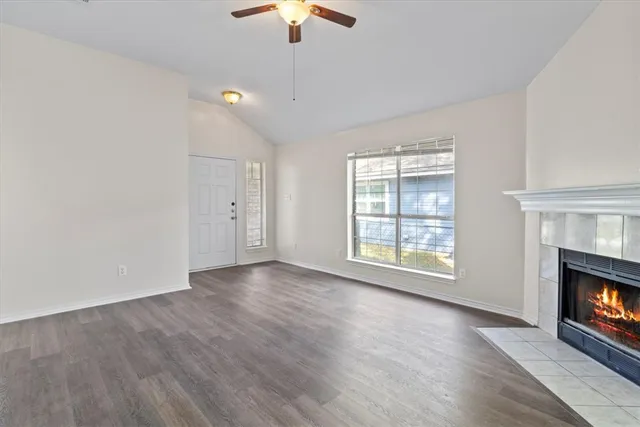 an empty room with wooden floor fireplace cabinet and windows