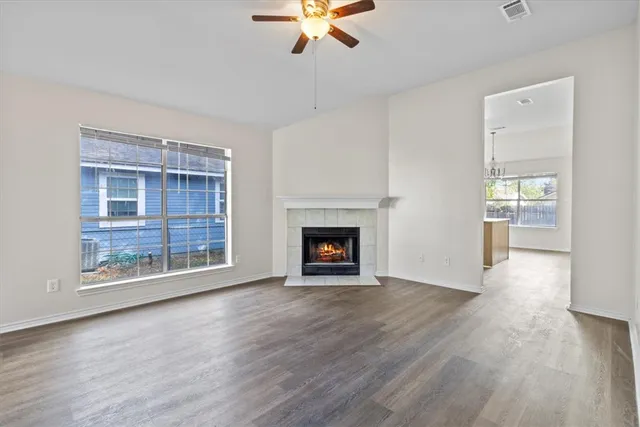 an empty room with wooden floor a fireplace and windows