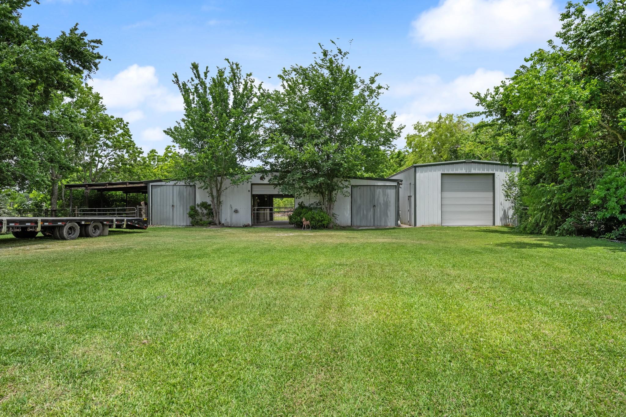 15602 Fir Road Santa Fe, TX 77517 - Photo 34 of 42 Versatile outbuildings include a horse barn and an insulated workshop, offering ample space for livestock, equipment storage, hobbies, or business use. Surrounded by mature trees and open green space, this setup is ideal for country living and recreational use.