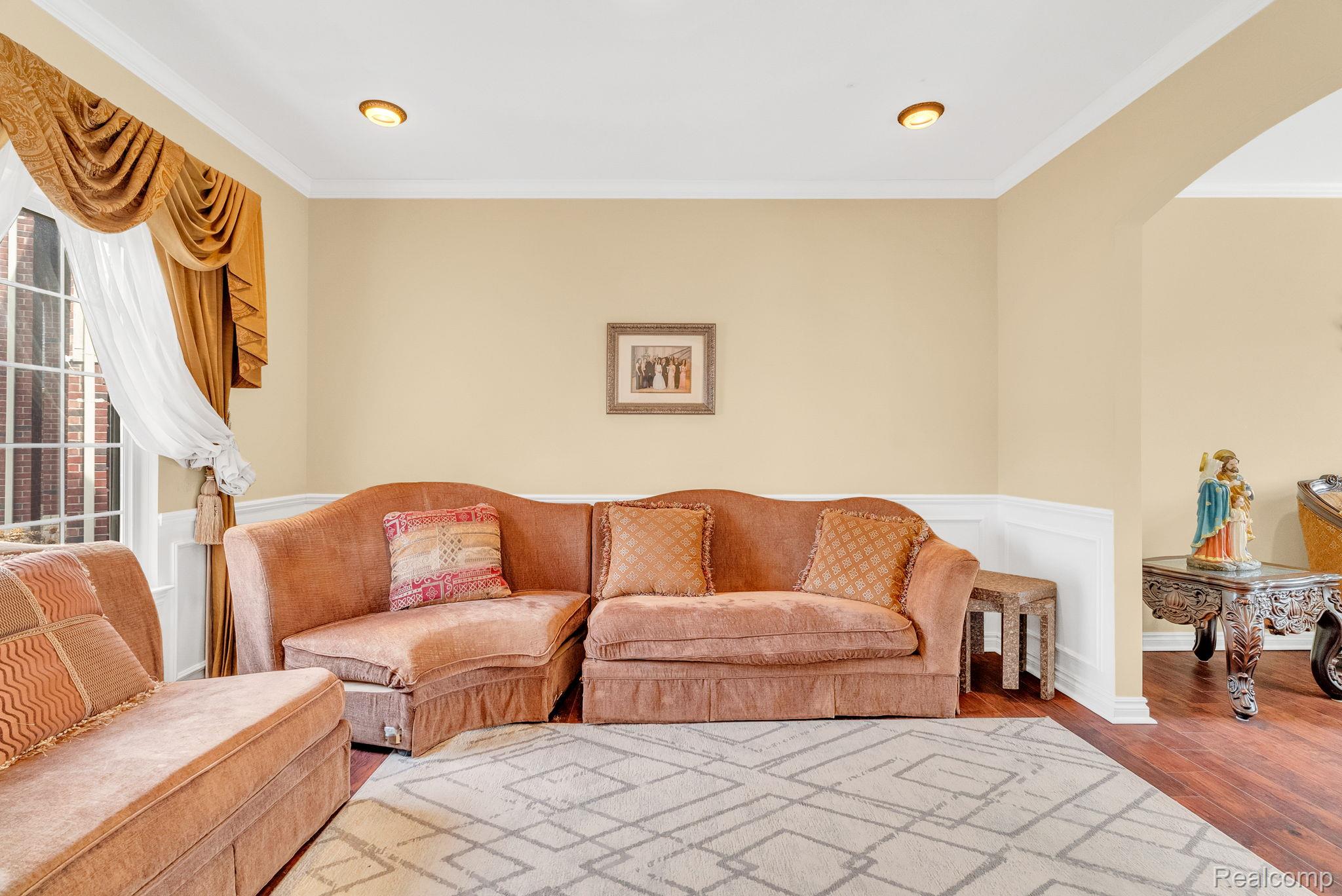 4122 Hawks Nest Road Utica, MI 48317 - Photo 17 of 74 Living room with crown molding, a wainscoted wall, wood-type flooring, arched walkways, and a decorative wall