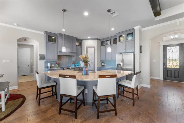 a dining room with stainless steel appliances kitchen island granite countertop a dining table chairs and a refrigerator