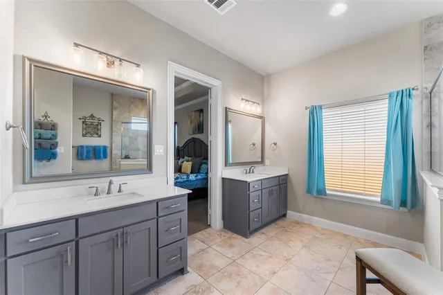 a spacious bathroom with double vanity a window a mirror and bathtub