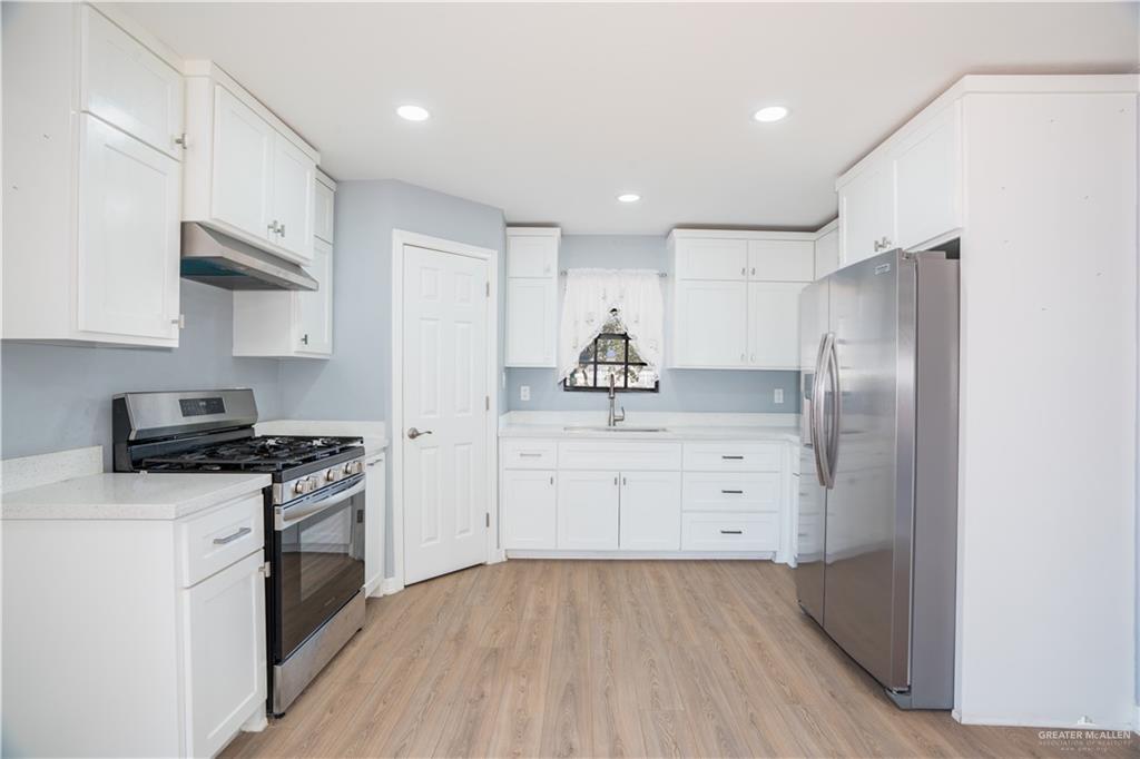 212 North Street Mission, TX 78572 - Photo 6 of 26 a kitchen with white cabinets and stainless steel appliances