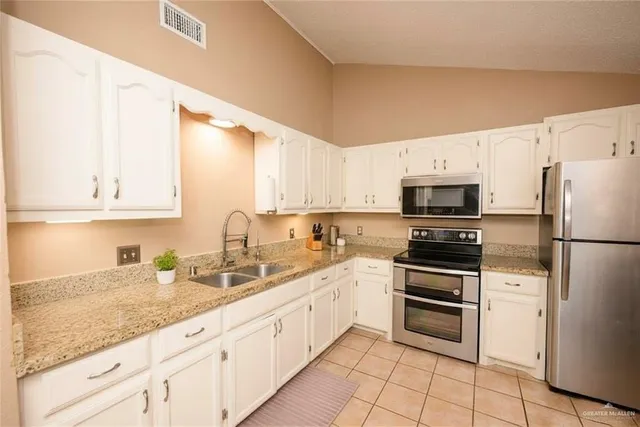 a kitchen with granite countertop white cabinets and white appliances