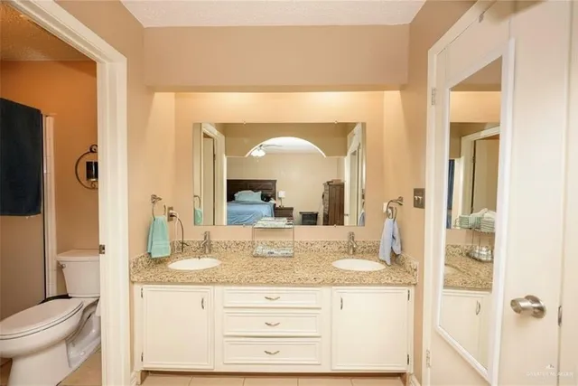 a bathroom with a granite countertop sink mirror vanity and toilet