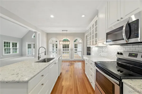 a kitchen with stainless steel appliances granite countertop a sink and stove top oven with wooden floor