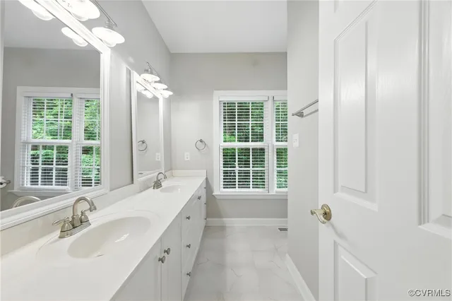 a bathroom with a tub sink double vanity and windows