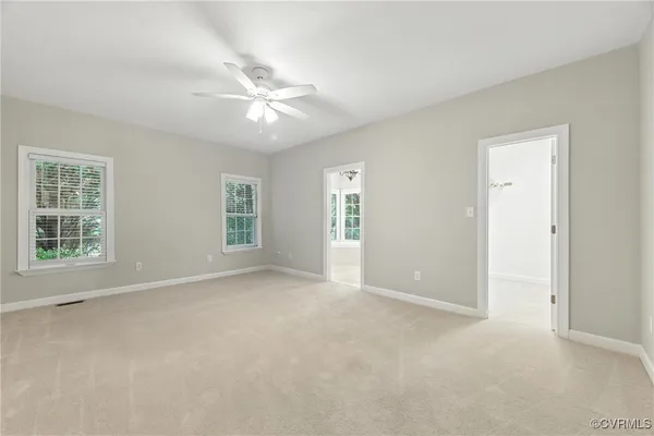 an empty room with windows and fan