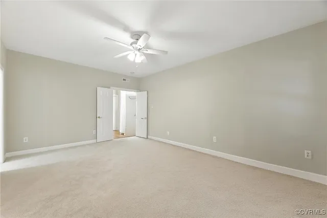 an empty room with a window and ceiling fan