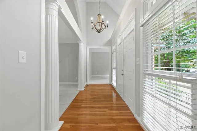 a view of a hallway with wooden floor and a chandelier