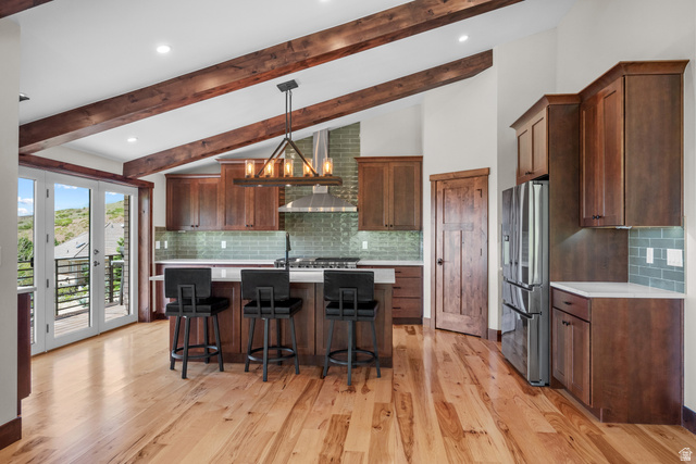 4221 Juniper Circle Alpine, UT 84004 - Photo 2 of 66 Spacious kitchen featuring exposed wood ceiling beams, wood-finish flooring, a central island with countertop seating, stainless steel appliances, and French doors opening to a balcony
