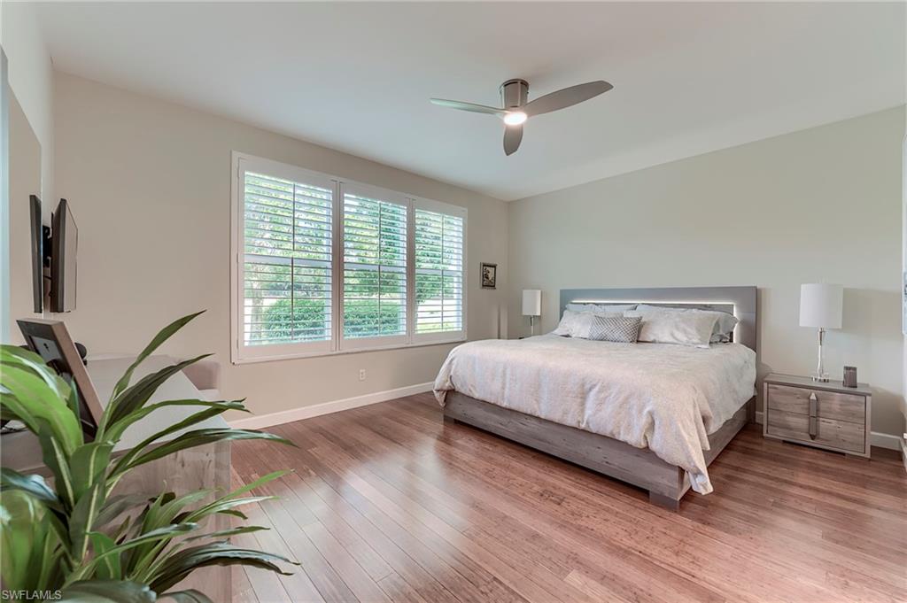 23815 Clear Spring Court, Unit 2105 Estero, FL 34135 - Photo 14 of 37 a bedroom with a bed lamp and a large window with wooden floor