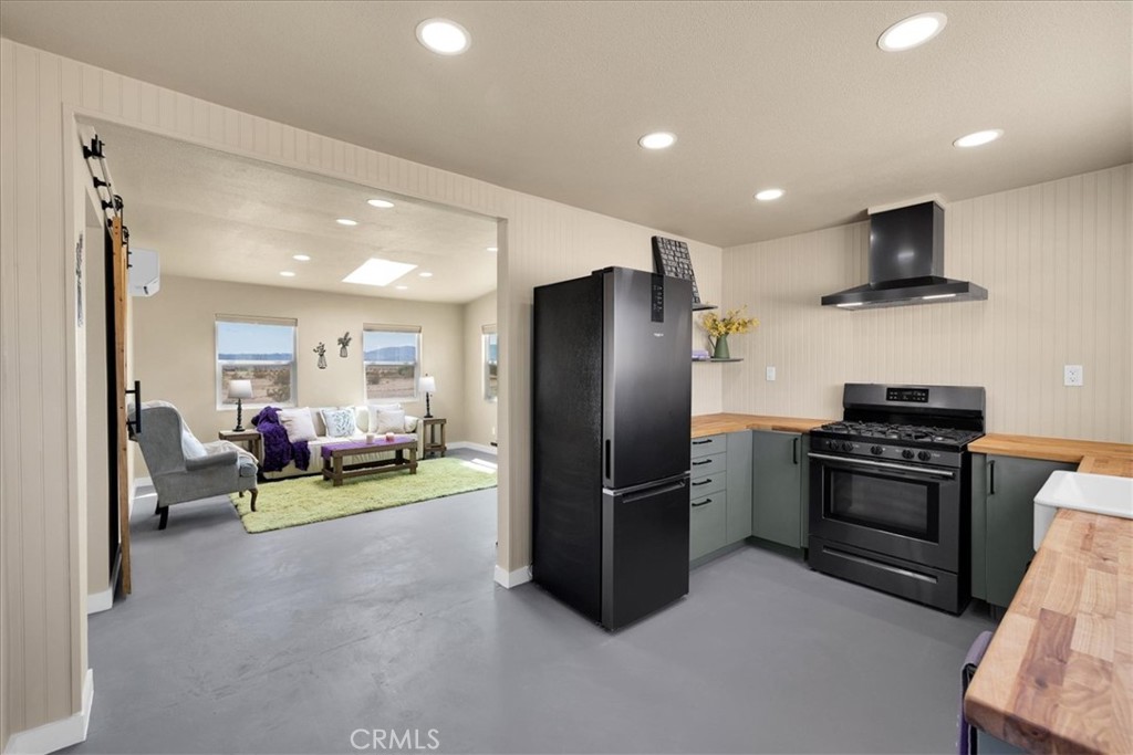 84320 McCombie Road Twentynine Palms, CA 92277 - Photo 11 of 57 a kitchen with stainless steel appliances kitchen island granite countertop a refrigerator and a stove top oven with wooden floor