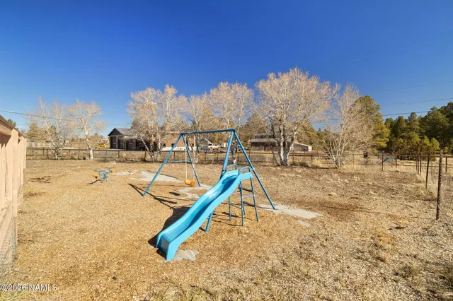 a view of a swimming pool with a bench and trees in the background