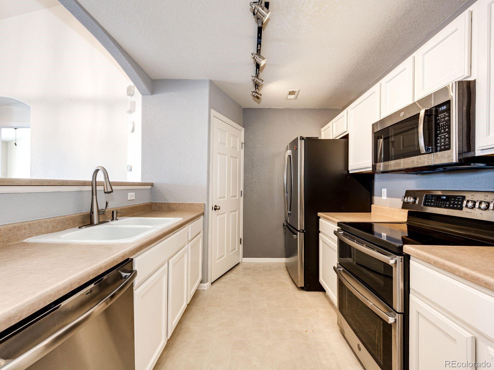 5255 Memphis Street, Unit 122 Denver, CO 80239 - Photo 13 of 26 a kitchen with stainless steel appliances a stove microwave and a sink