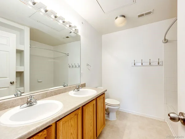 a spacious bathroom with a granite countertop sink a toilet and a mirror