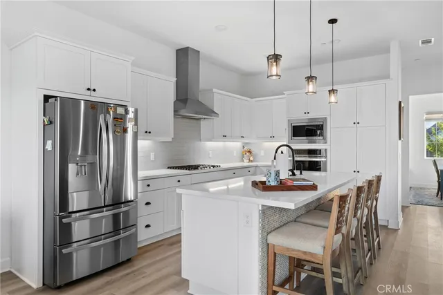 a kitchen with stainless steel appliances granite countertop a sink a stove a refrigerator and island with wooden floor