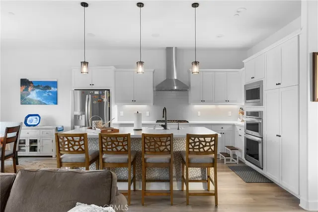 a open kitchen with stainless steel appliances granite countertop a stove and white cabinets with wooden floor